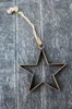 A rusty metal star ornament hangs from a jute string against a weathered wooden background. Produktbild-Vorschau