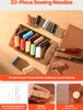A collection of sewing needles and threads, along with leatherworking tools, laid out on a wooden surface. Produktbild-Vorschau