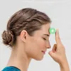 A woman is shown with her eyes closed, holding a small green foam roller to her forehead. Anteprima dell’immagine prodotto
