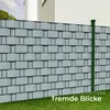 A fence with privacy screen inserts and a green post, with grass in the foreground and a building in the background. Náhled obrázku produktu