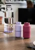 A glass bottle filled with water and two smaller containers on a wooden table. Produktbild-Vorschau