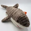 A plush toy shark with tiger stripes is lying on a white surface. Produktbild-Vorschau