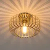 A close-up shot of a gold-colored ceiling light fixture with a wire cage design, casting intricate shadows on the ceiling. Náhled obrázku produktu