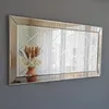 A rectangular mirror with a decorative frame and a diamond pattern in the center, hanging on a gray wall. A vase with dried flowers is reflected in the mirror. Produktbild-Vorschau