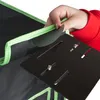 A hand is shown attaching a black panel with slots and screws to a black and green fabric item, likely a grow tent. Náhled obrázku produktu