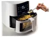 A hand pouring oil into an air fryer filled with french fries. Náhled obrázku produktu