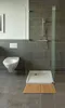 A modern bathroom with a toilet, shower, and a bamboo mat. Produktbild-Vorschau
