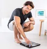 A man is crouching on the floor in a bathroom, interacting with a digital scale. Produktbild-Vorschau