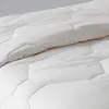 A close-up view of a white, quilted blanket. Produktbild-Vorschau