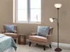 A floor lamp with two lights stands next to two armchairs in a room with a window. Náhled obrázku produktu