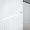 A close-up view of a white cabinet with vertical grooved panels and a drawer. Anteprima dell’immagine prodotto