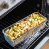 A glass baking dish filled with pasta and vegetables, topped with melted cheese and parsley, is placed on an oven rack inside an open oven. Produktbild-Vorschau