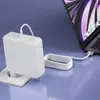 A white Macbook Pro charger is plugged into a wall socket and connected to a Macbook Pro laptop. Produktbild-Vorschau
