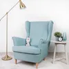 A light blue armchair with a plush toy Olaf sitting on it, next to a small side table with a plant, a vase, and an alarm clock. A floor lamp is to the left. Podgląd zdjęcia produktu
