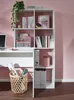 A white desk with a white shelf unit filled with books and decorative items, set against a pink wall. Voir les images du produit