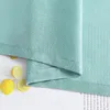 A close-up of a green fabric with lemons and text in the background. Produktbild-Vorschau