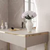 A close-up view of a modern vanity table with a vase of flowers and some cosmetic items. Produktbild-Vorschau