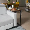 A C-shaped side table is placed next to a sofa, holding a cup of coffee and a croissant. Produktbild-Vorschau