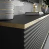 A close-up view of a black TV cabinet with a gold trim and fluted detailing on the side. Produktbild-Vorschau