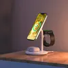 A white 3-in-1 wireless charging stand with a phone, smartwatch, and earbuds on it, placed on a wooden desk. Produktbild-Vorschau