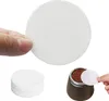 A hand holding a round coffee filter paper, with a stack of filters and a coffee maker with coffee grounds in the background. Produktbild-Vorschau