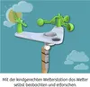 A children's weather station with various components like a sun, clouds, anemometer, and wind vane, set against a blue background with cartoon clouds. Produktbild-Vorschau