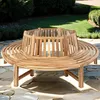 A circular wooden bench is placed on a stone patio in a garden setting. Produktbild-Vorschau