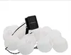 A string of white paper lantern-shaped lights with a solar panel charger. Produktbild-Vorschau