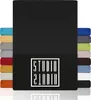 A stack of fabric swatches in various colors, with a large black swatch dominating the foreground and a logo on the lower portion. Produktbild-Vorschau