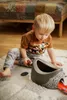 A young boy is sitting on a rug and playing with a toy. Náhľad obrázku produktu