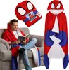 A man is sitting on a couch reading a book while wearing a Spider-Man hooded blanket. Náhled obrázku produktu