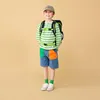 A young boy wearing a backpack and a striped shirt stands against a plain background. Produktbild-Vorschau