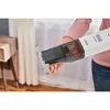A person is holding a white and gray handheld vacuum cleaner with a transparent dustbin. Produktbild-Vorschau