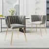 Two gray velvet dining chairs with gold metal frames are shown in a dining room setting. Anteprima dell’immagine prodotto