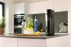 A kitchen counter with a water carbonator, bottles, glasses, and fruit. Anteprima dell’immagine prodotto
