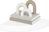 A decorative sculpture with arched elements on top of two books, placed on a white shelf. Voir les images du produit