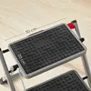 Close-up view of a two-step folding ladder, showing the textured surface of the steps and measurement indicators. Produktbild-Vorschau