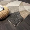 A close-up view of a geometric patterned rug with a woven pouf and a rolled magazine. Produktbild-Vorschau