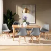 A dining room setting with a wooden table and chairs, a large plant, and artwork on the wall. Náhled obrázku produktu