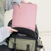 A person is placing a pink laptop sleeve into a backpack. Produktbild-Vorschau