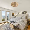 A bedroom with a bed, dresser, and a door leading to a balcony overlooking the ocean. Produktbild-Vorschau