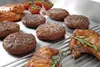 A close-up shot of various grilled meats and cherry tomatoes on a grill. Produktbild-Vorschau