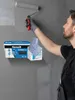 A man is painting a wall with a roller, and a product container is placed on the wall. Produktbild-Vorschau