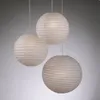 Three beige paper lanterns hanging from white cords against a gray background. Produktbild-Vorschau