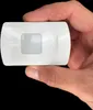A hand holding a small white electronic device. Produktbild-Vorschau