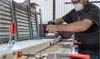 A person is sanding a piece of wood on a workbench. Náhľad obrázku produktu