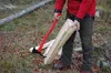 A person is using a red and black hand axe to split a piece of wood in a forest setting. Produktbild-Vorschau