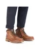A person's legs wearing navy blue trousers and brown leather boots. Produktbild-Vorschau