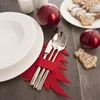 A Christmas-themed table setting with plates, cutlery in a festive holder, and gingerbread cookies. Voir les images du produit