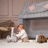 A baby playing with a balance bike and a wooden car next to a play tent. Náhľad obrázku produktu